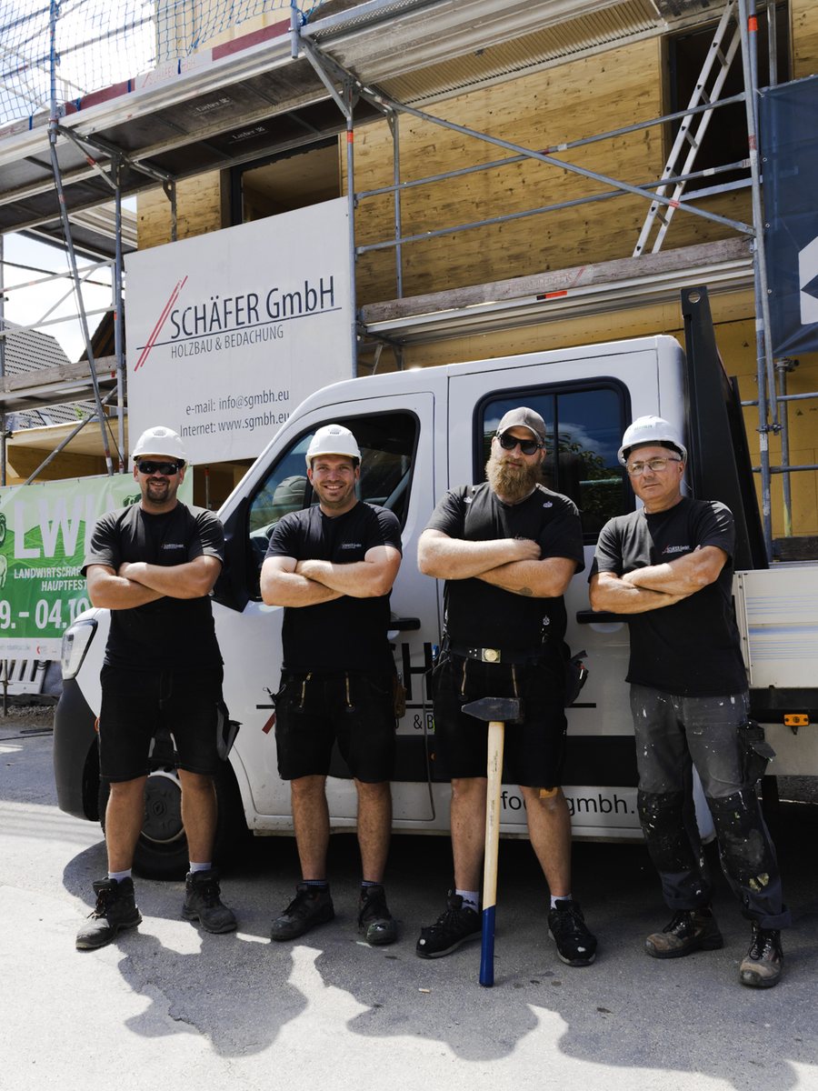 Fünf Mitarbeiter der Schäfer GmbH in Arbeitskleidung und mit Helmen vor dem Firmentransporter
