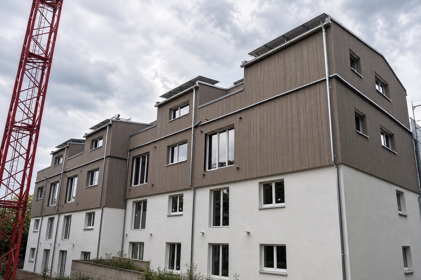 Mehrfamilienhaus mit aufgestocktem Holzbau und vorgehängter Holzfassade, Kran an der Fassade